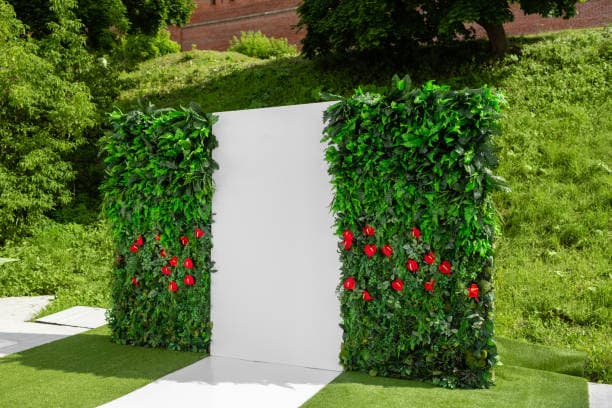 White event backdrop framed with greenery and red floral accents